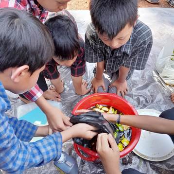 A group of children around a red bucket.